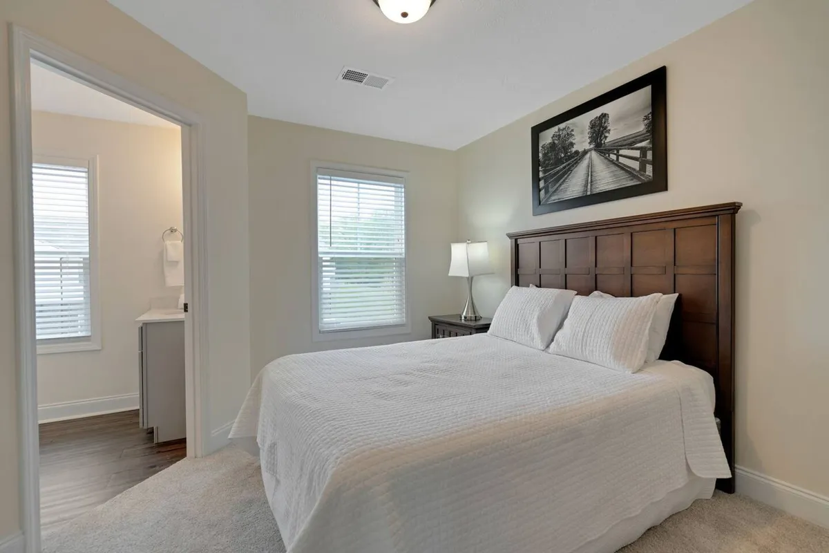 A peaceful bedroom with a cozy bed, bedside lamp, large window letting in morning sunlight, and calming wall art. The setting is designed for relaxation, providing a serene environment perfect for resting after a busy day.
