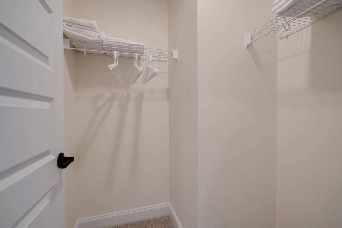 A neatly organized linen closet with clean towels stacked on wire shelving and hangers ready for use, exuding a sense of order and readiness.