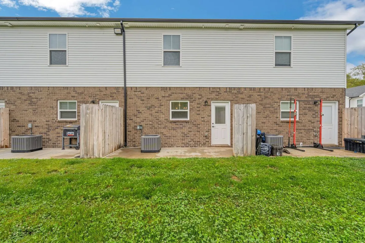 A welcoming backyard space with brick walls, windows, fencing, and a sunny patio area—ideal for outdoor gatherings, family dinners, or casual relaxation. The atmosphere is friendly and inviting, reflecting opportunities for togetherness outdoors.